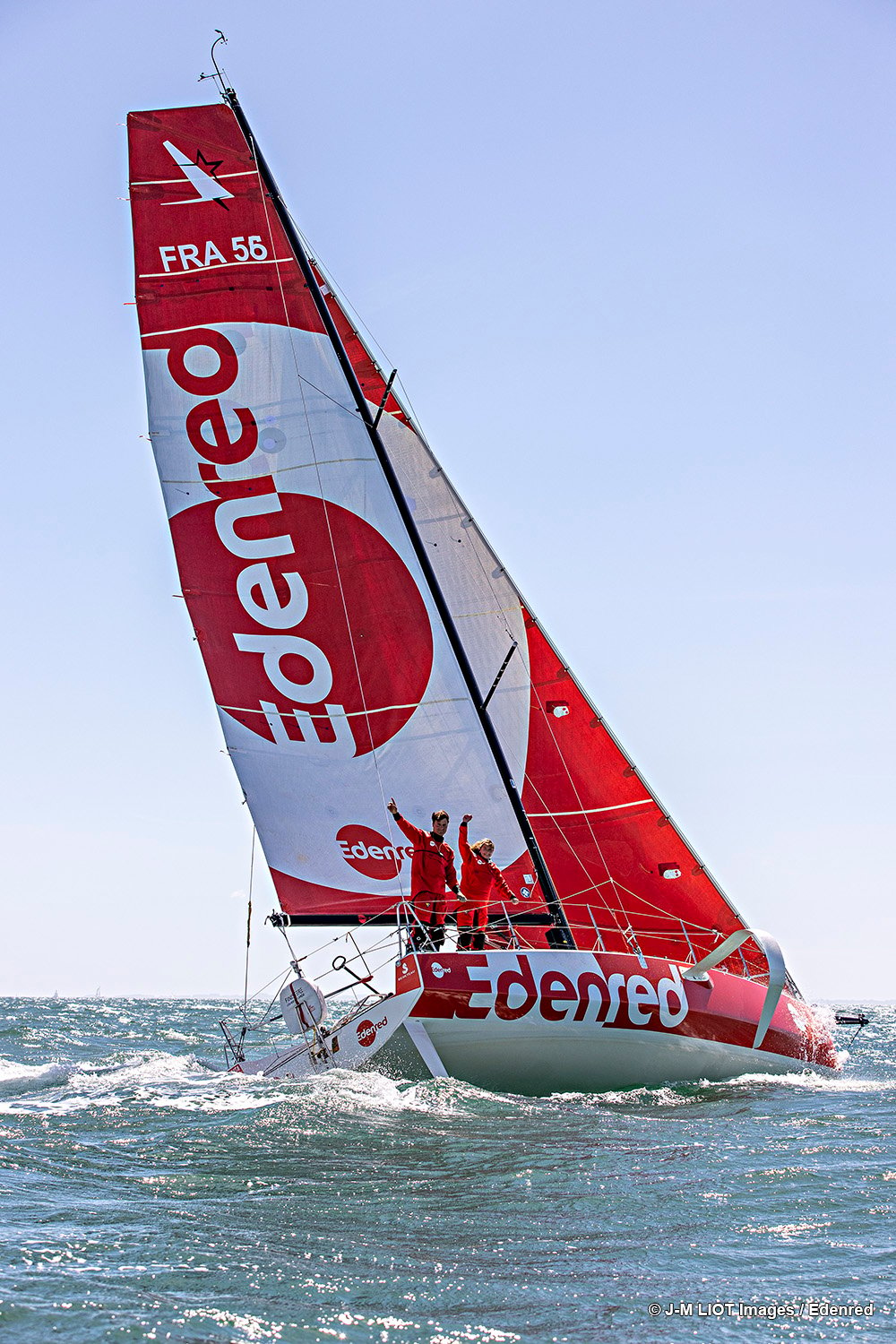 a boat with the red Edenred logo on it's sails and two men standing on the boat, both wearing red outfits that match the logo