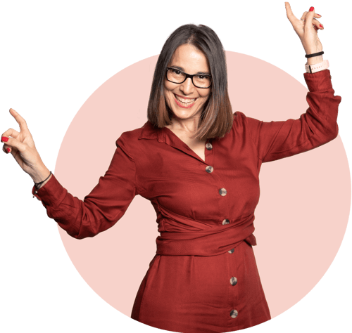 A woman shown with her arms raising and fingers pointing upwards wearing a red dress and smiling