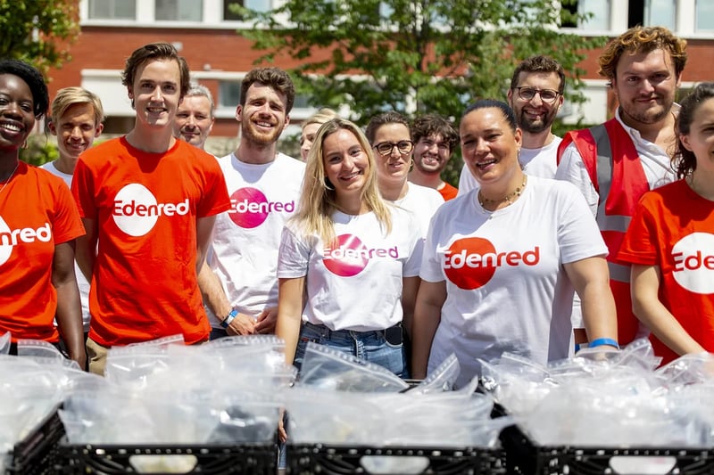 an image showing over a dozen workers in Edenred tshirts that are both red and white volunteering while carrying baskets and plastic bags